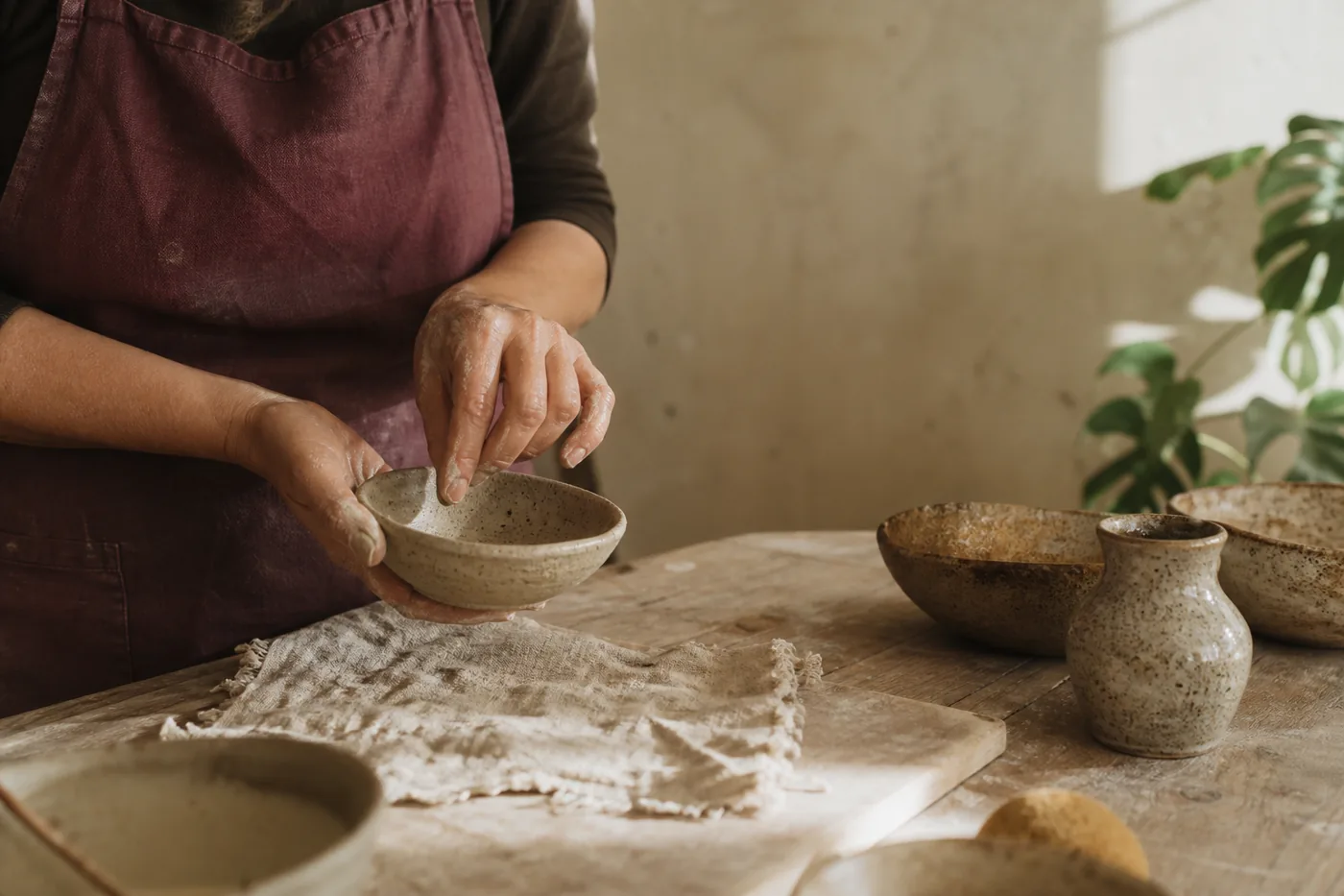 Hands of a fictional beginner pottery maker shaping a bowl